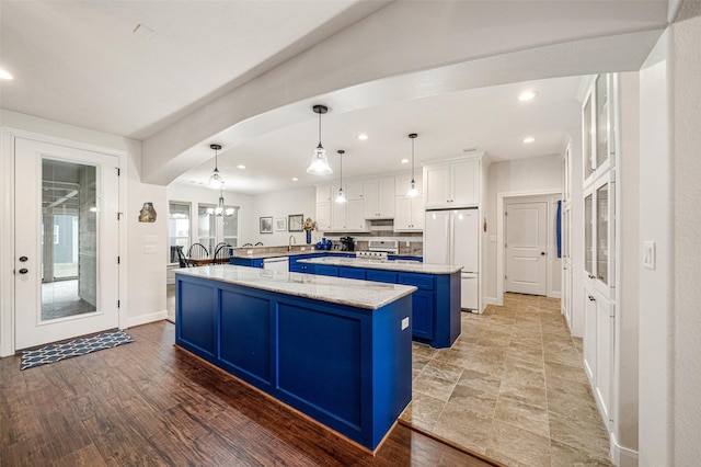 kitchen featuring blue cabinetry, pendant lighting, hardwood / wood-style floors, white fridge, and white cabinetry