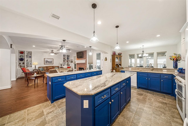 kitchen with white dishwasher, stainless steel gas stove, blue cabinetry, decorative light fixtures, and a kitchen island