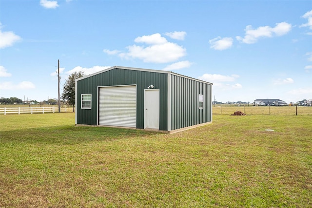 view of outbuilding featuring a lawn, a rural view, and a garage