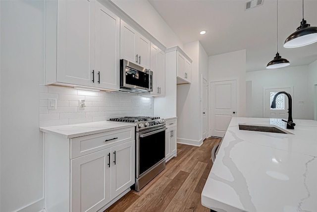 kitchen featuring pendant lighting, sink, white cabinetry, and stainless steel appliances