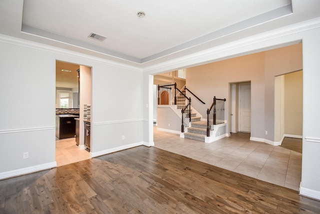 spare room with hardwood / wood-style flooring, a raised ceiling, and ornamental molding