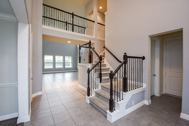 stairway featuring tile patterned flooring, a towering ceiling, and crown molding