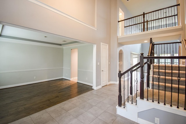 tiled foyer entrance featuring a towering ceiling and crown molding