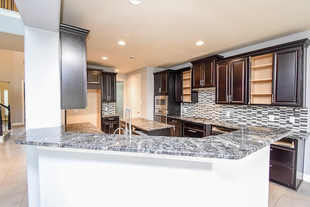 kitchen featuring kitchen peninsula, stainless steel appliances, sink, dark stone countertops, and light tile patterned flooring