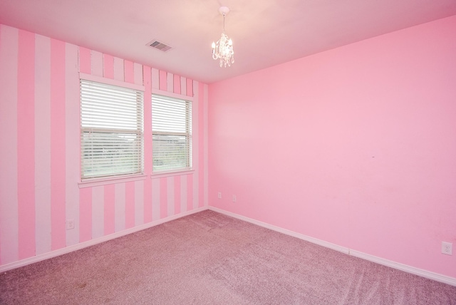 carpeted empty room featuring a chandelier