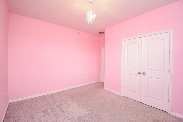 unfurnished bedroom with a chandelier, a closet, and light colored carpet