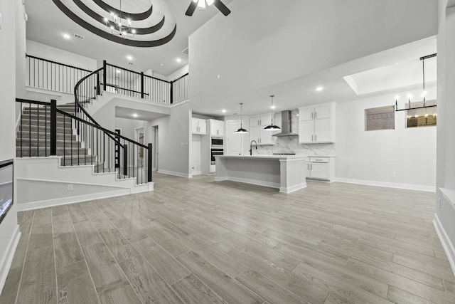 unfurnished living room featuring a high ceiling, a tray ceiling, light hardwood / wood-style flooring, and sink