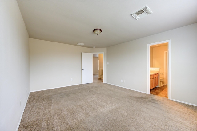 unfurnished bedroom featuring light carpet and connected bathroom