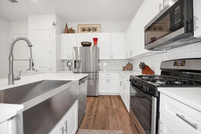 kitchen featuring backsplash, white cabinetry, dark hardwood / wood-style flooring, and stainless steel appliances