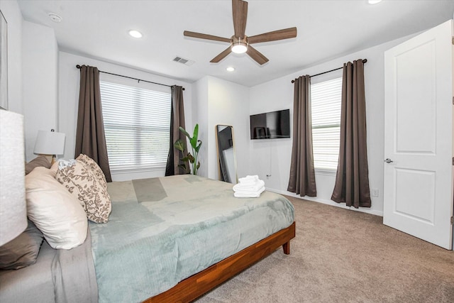 bedroom featuring multiple windows, ceiling fan, and light carpet