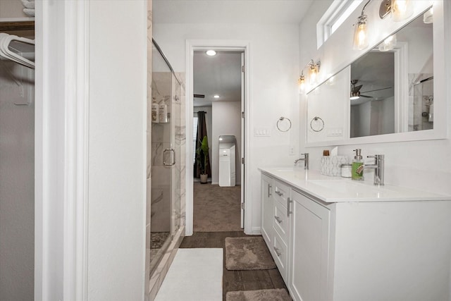 bathroom featuring a shower with shower door, ceiling fan, wood-type flooring, and vanity