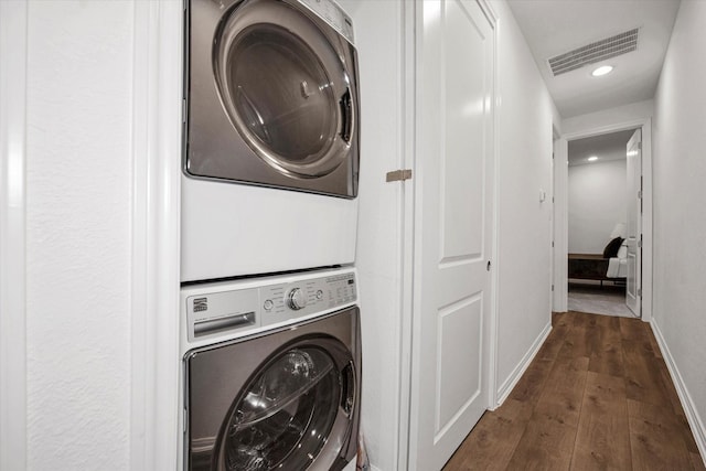 laundry area with dark hardwood / wood-style flooring and stacked washer and dryer