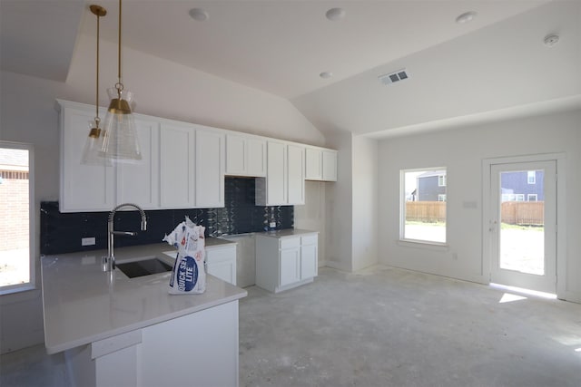 kitchen with visible vents, a sink, vaulted ceiling, white cabinets, and pendant lighting