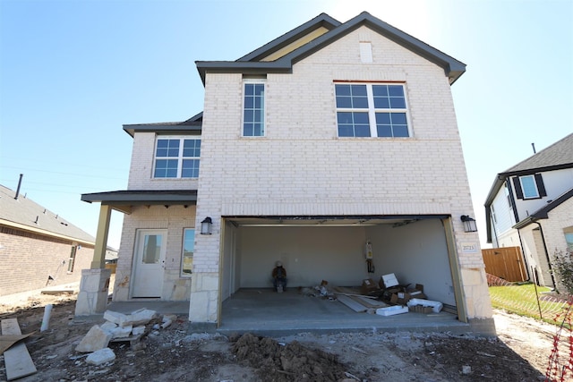 view of front of home featuring an attached garage, fence, and brick siding