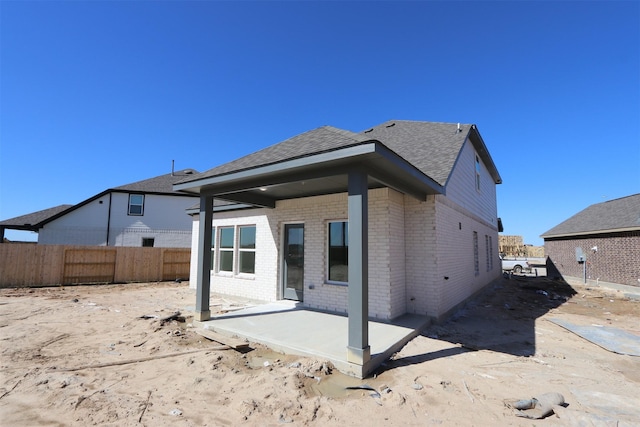 back of property with a patio, fence, brick siding, and a shingled roof