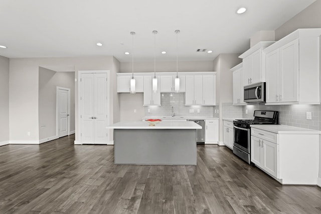 kitchen featuring pendant lighting, a center island, white cabinets, sink, and appliances with stainless steel finishes