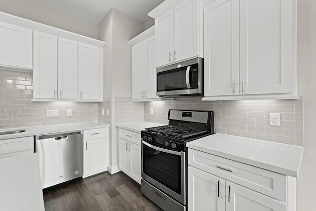 kitchen with white cabinets, dark hardwood / wood-style floors, decorative backsplash, and appliances with stainless steel finishes