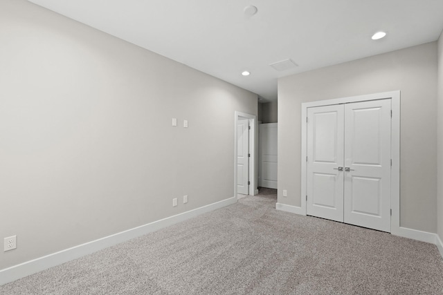 unfurnished bedroom with a closet and light colored carpet