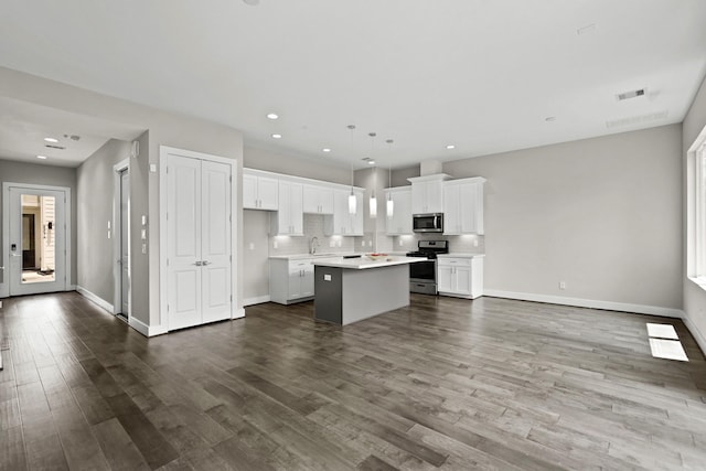 kitchen featuring stainless steel appliances, a kitchen island, hardwood / wood-style floors, decorative light fixtures, and white cabinets