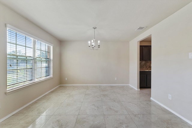 empty room with an inviting chandelier and light tile patterned flooring