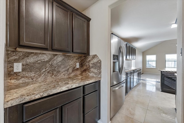 kitchen with tasteful backsplash, stainless steel fridge, vaulted ceiling, dark brown cabinets, and light tile patterned floors