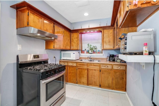 kitchen featuring ventilation hood, gas stove, sink, and a textured ceiling