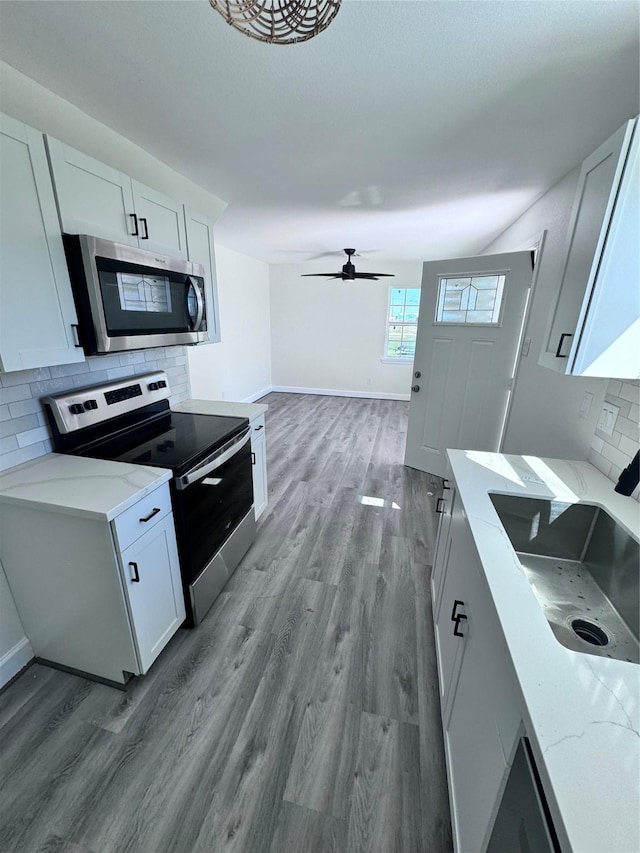 kitchen with backsplash, white cabinets, sink, light hardwood / wood-style flooring, and appliances with stainless steel finishes