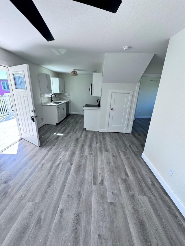 unfurnished living room featuring a textured ceiling, sink, and light hardwood / wood-style flooring