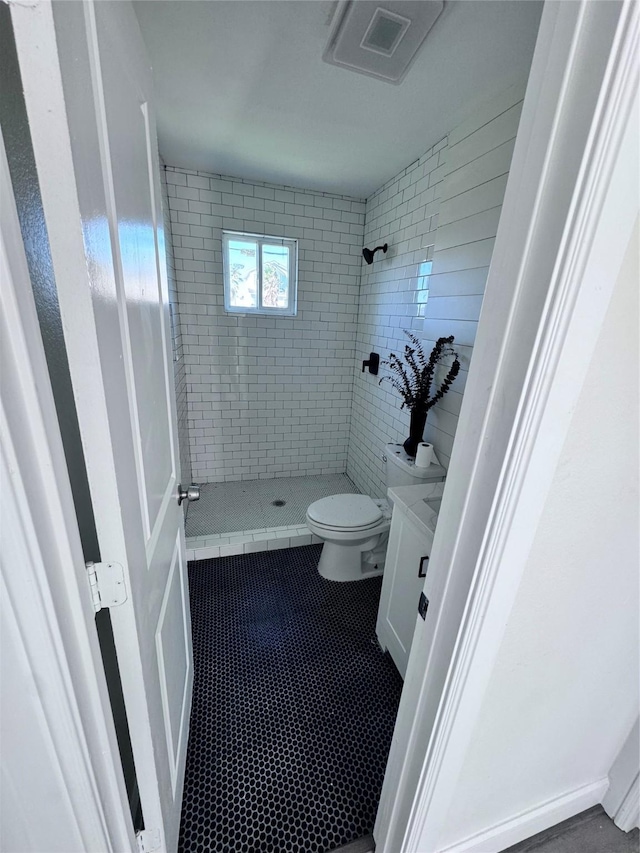 bathroom featuring tiled shower, vanity, and toilet