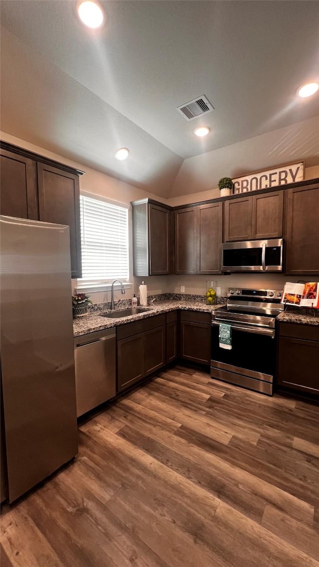 kitchen featuring dark wood-type flooring, dark brown cabinets, stainless steel appliances, and lofted ceiling