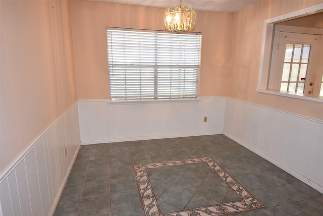 tiled spare room featuring an inviting chandelier