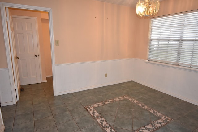 unfurnished room with an inviting chandelier and dark tile patterned floors