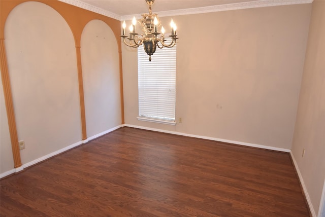 empty room featuring a chandelier, dark hardwood / wood-style floors, and crown molding