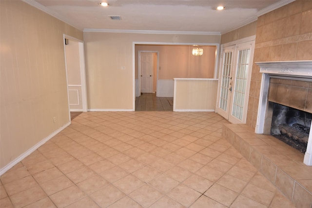 unfurnished living room featuring a tiled fireplace, crown molding, and french doors