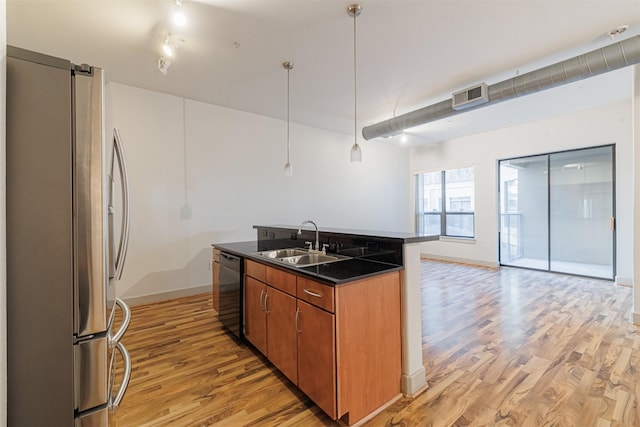 kitchen with sink, hanging light fixtures, black dishwasher, light hardwood / wood-style flooring, and stainless steel fridge