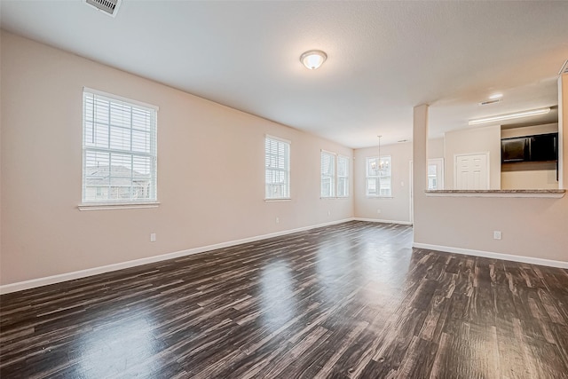 unfurnished living room featuring a chandelier and dark hardwood / wood-style flooring