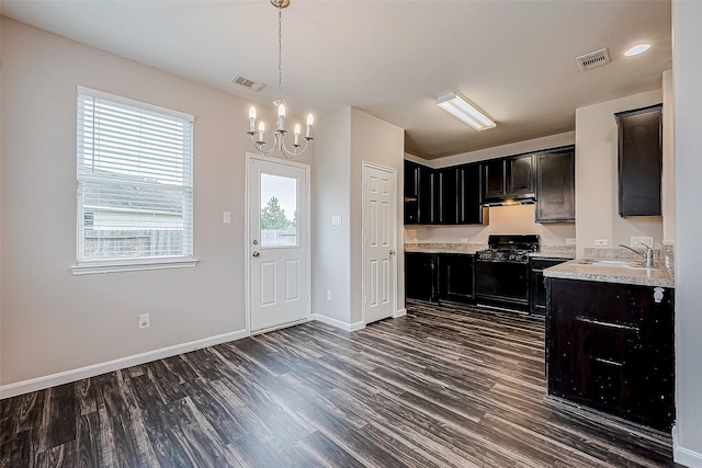 kitchen featuring gas stove, sink, an inviting chandelier, dark hardwood / wood-style floors, and hanging light fixtures