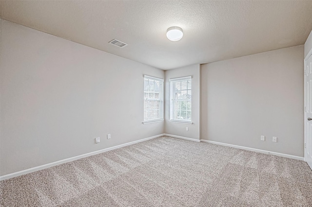 carpeted spare room with a textured ceiling