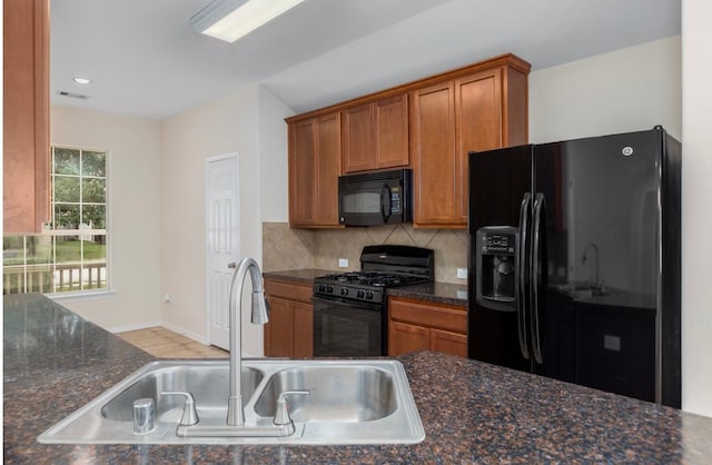 kitchen with backsplash, dark stone countertops, sink, and black appliances