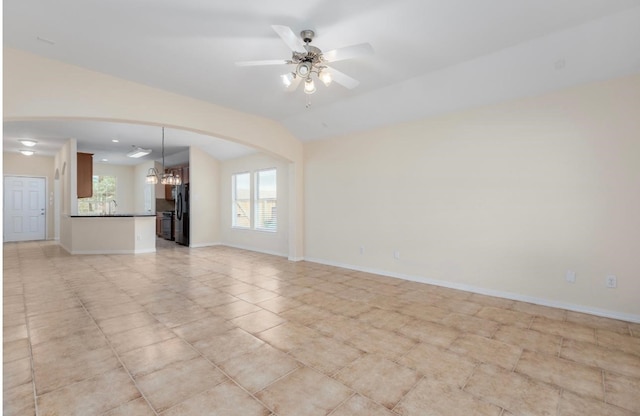 unfurnished living room featuring sink and ceiling fan with notable chandelier