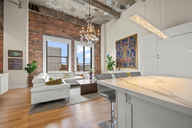 interior space featuring a high ceiling, light hardwood / wood-style floors, brick wall, and an inviting chandelier