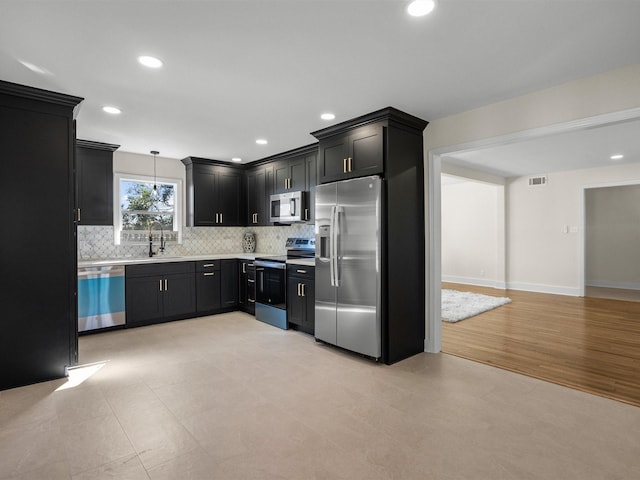 kitchen featuring decorative backsplash, stainless steel appliances, sink, light hardwood / wood-style floors, and hanging light fixtures