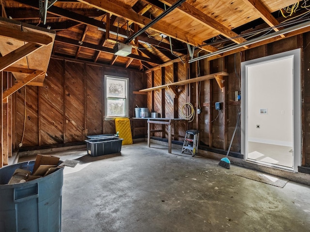 misc room featuring concrete flooring, lofted ceiling, and wooden walls