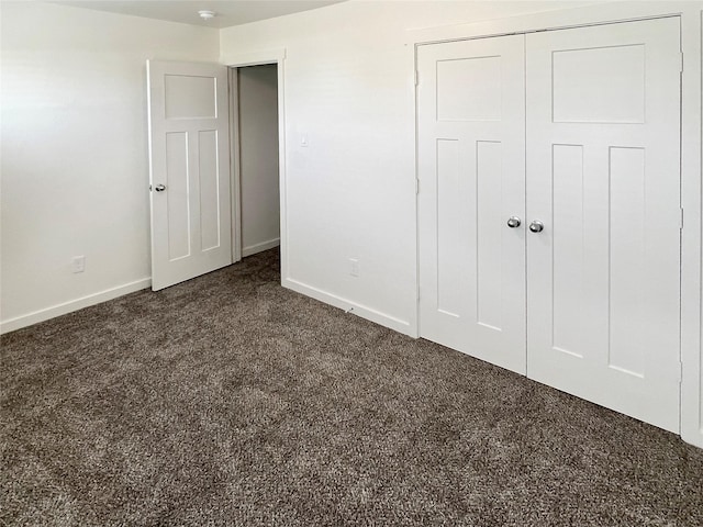 unfurnished bedroom with dark carpet and a closet