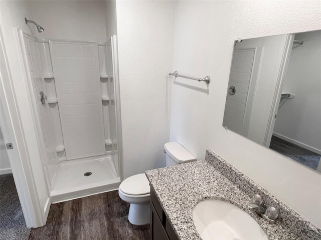 bathroom featuring hardwood / wood-style floors, vanity, toilet, and a shower