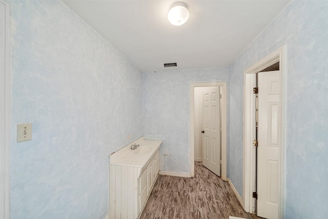 corridor with light hardwood / wood-style floors and sink