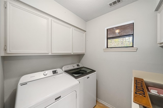 clothes washing area with cabinets, independent washer and dryer, and a textured ceiling