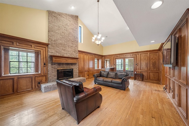 living room with plenty of natural light, a fireplace, high vaulted ceiling, and light hardwood / wood-style flooring