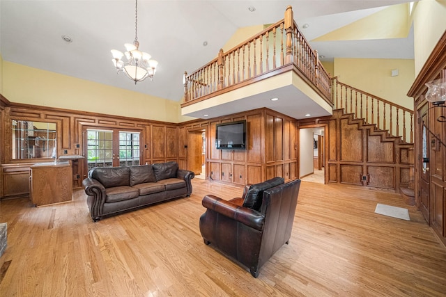 living room featuring an inviting chandelier, light hardwood / wood-style flooring, and high vaulted ceiling