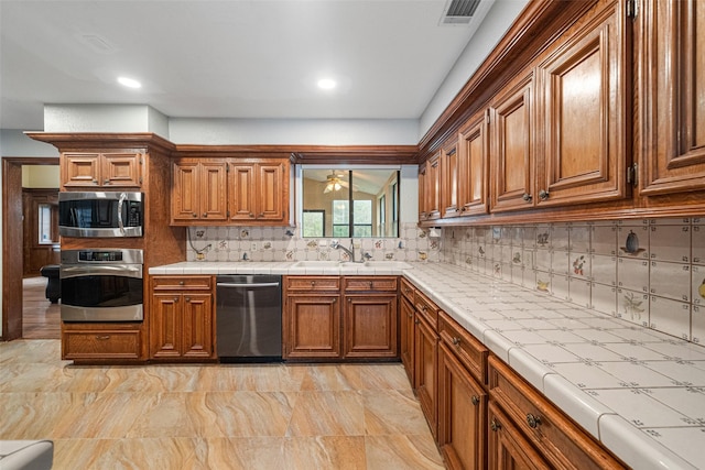 kitchen with backsplash, tile countertops, sink, and stainless steel appliances